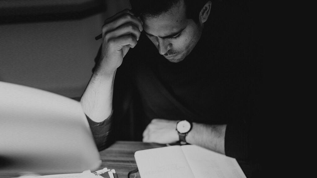 Crop pondering man analyzing expenses and taking notes