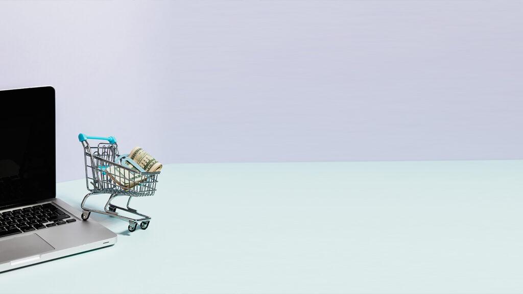 Shopping Cart with Money on top of a Laptop