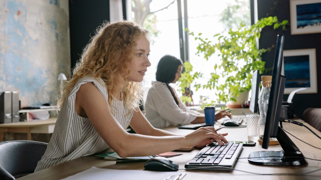 Lady sits at desk typing in office