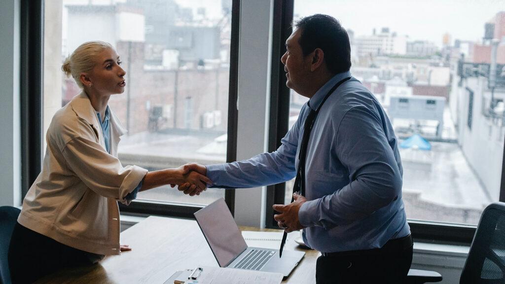 Young woman shaking hands with boss after business presentation