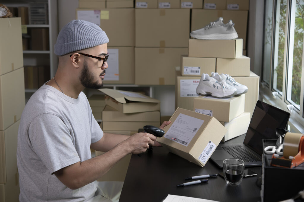 A casual worker managing online retail orders, scanning packages in a home-based shipping station