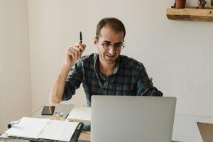 A virtual bookkeeper gesturing during a work session at his desk with a laptop