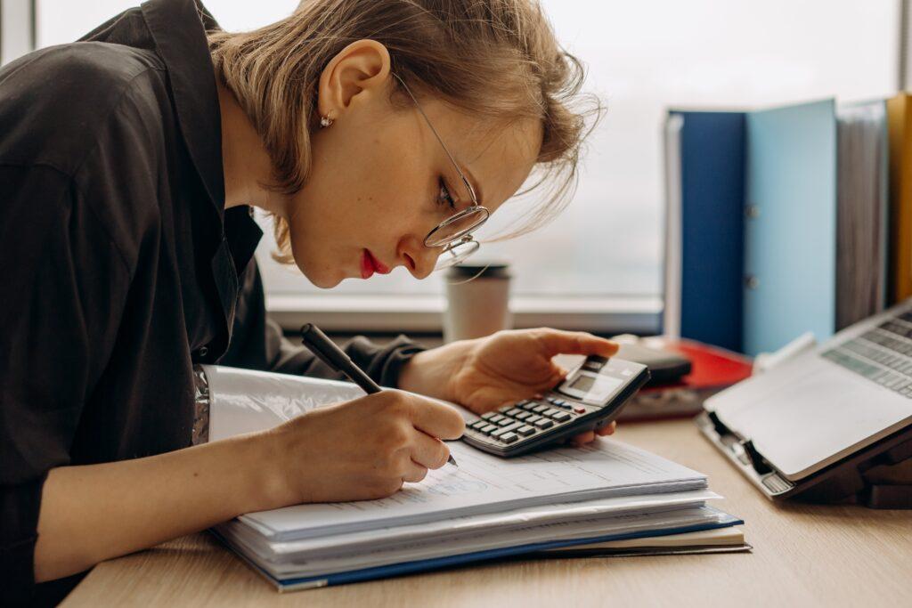 bookkeeper intently using a calculator and taking notes at her desk