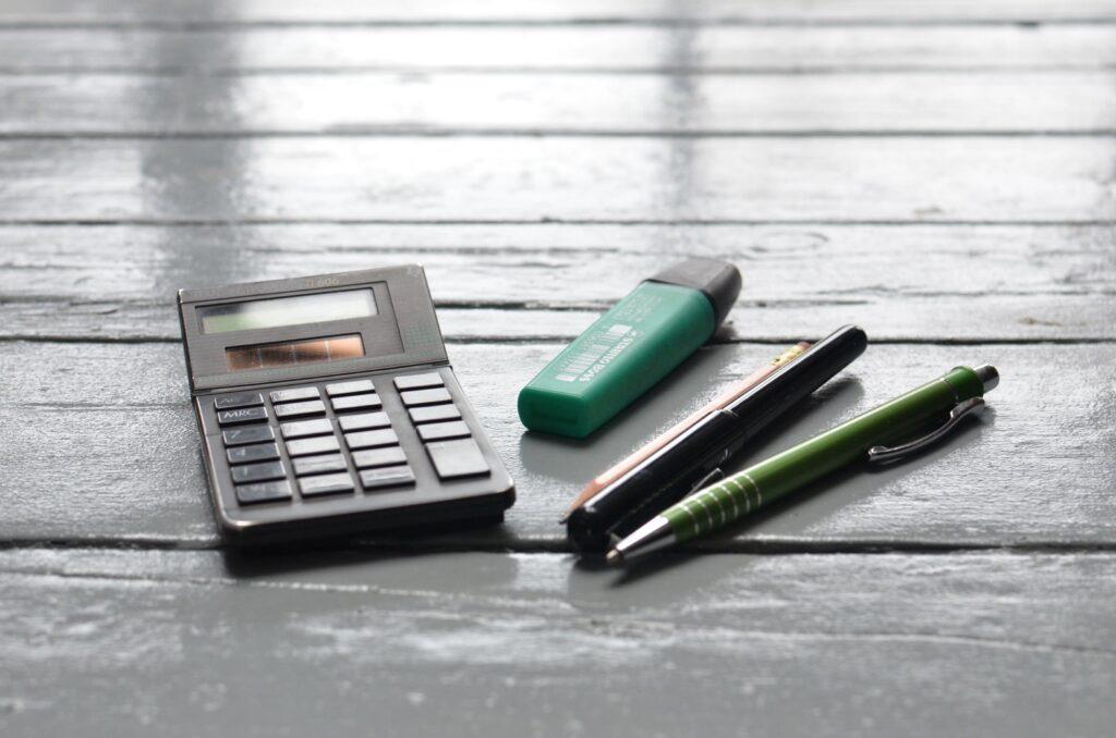 Office supplies including a calculator, a green eraser, and two pens